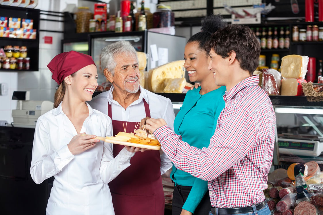 Salespeople Offering Cheese Samples to Customers in Shop